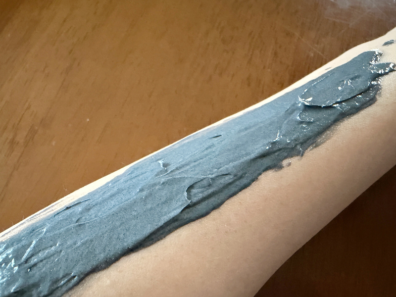 泥パックのように濃厚な「つるるんたん」の黒いクリームを腕に塗り広げた状態