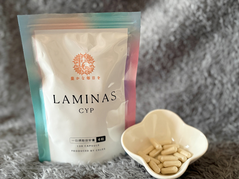 グレーの背景に映えるLAMINAS CYP（ラミナスCYP）のパッケージと小皿に盛られたカプセル