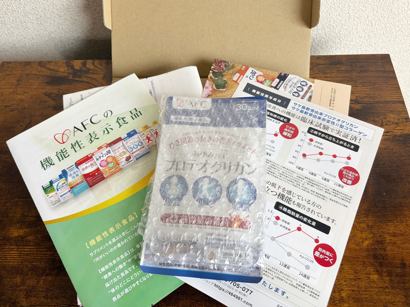 あゆみの宝の段ボール箱を開封した中身と、緩衝材に包まれた本品、同梱のパンフレット一覧