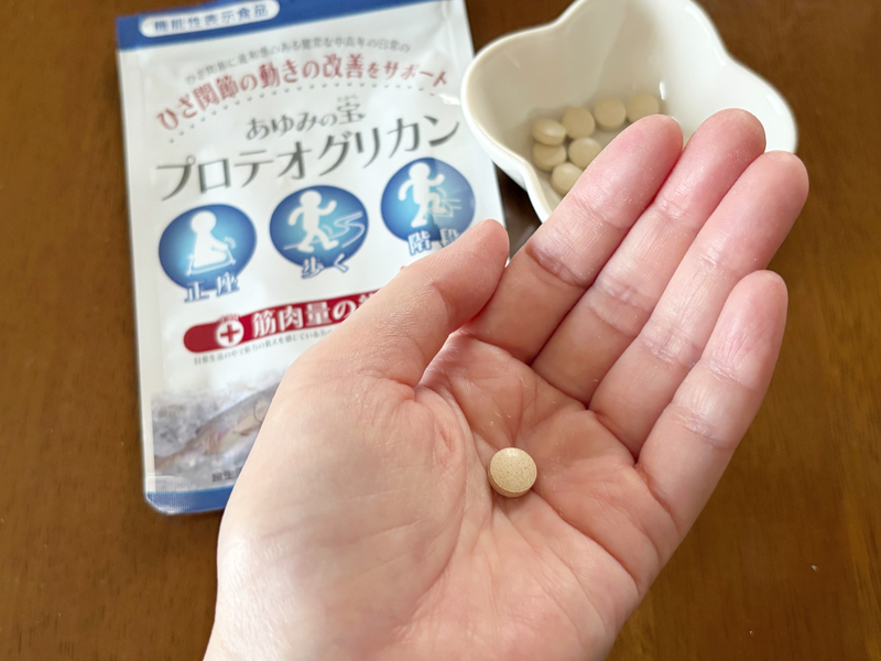 手のひらの上に乗せた、ベージュがかったあゆみの宝のサプリメント1粒のサイズ感