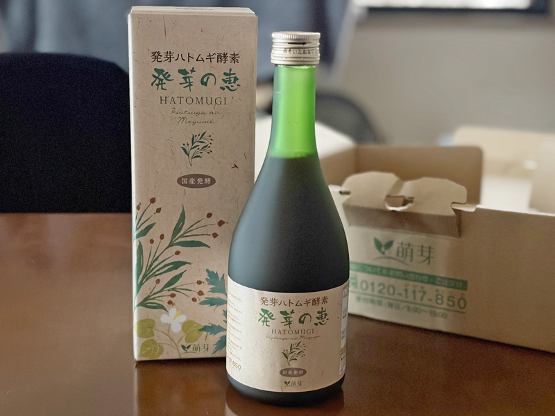 テーブルの上に並べられた発芽の恵のボトル、外箱、炭酸割りの入ったグラス、パンフレットの全体像